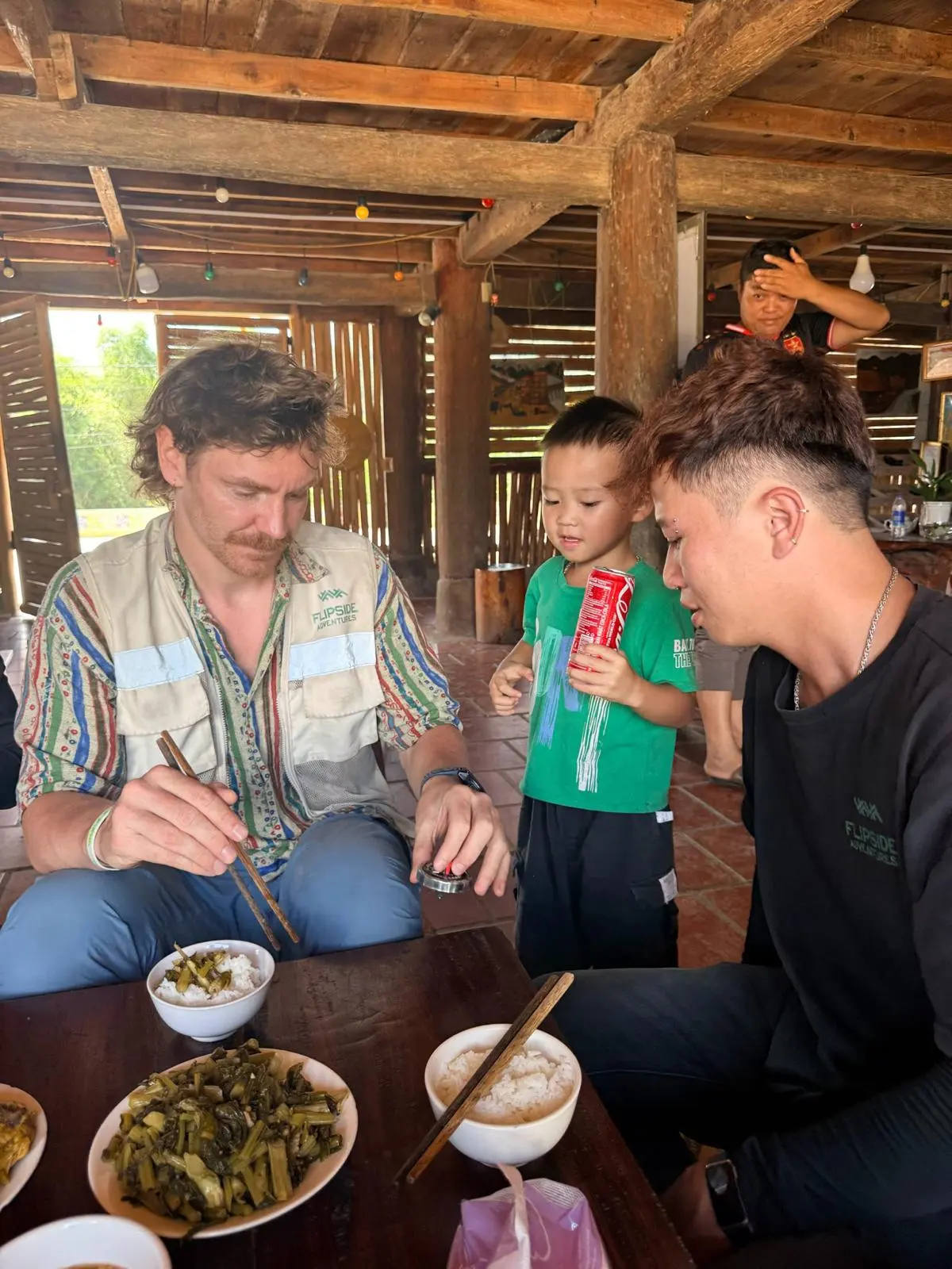 A guest eating with his guide while a local boy watches over the table