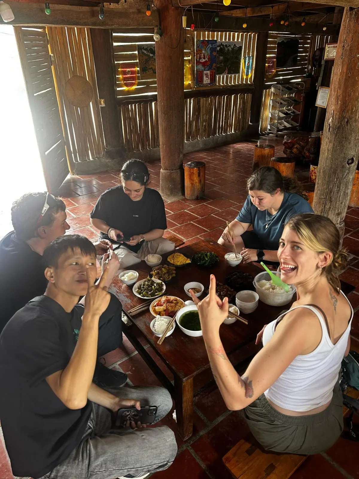 Riders and their guide round a low table of breakfast dishes at a homestay