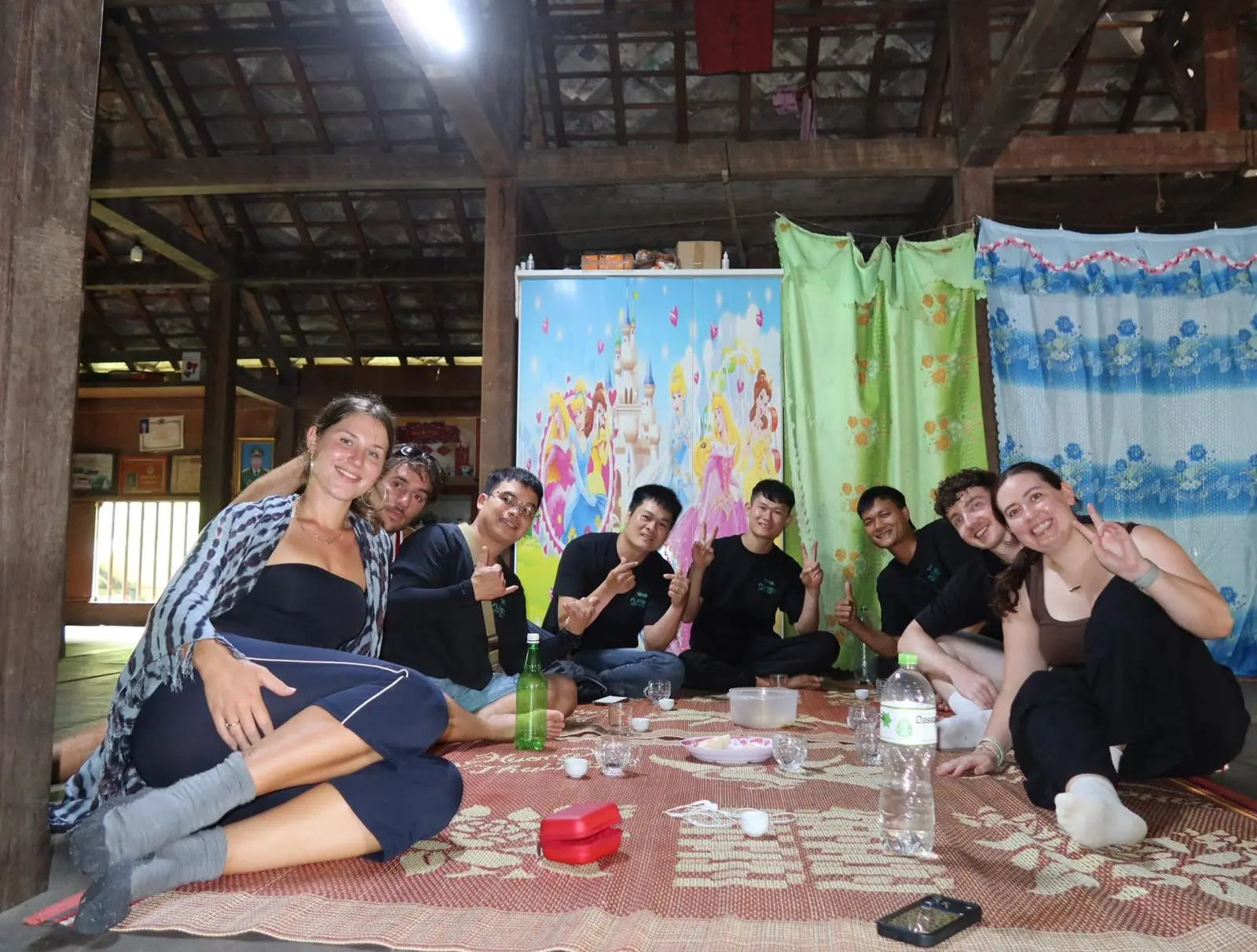 Guests and guides sitting on the mat inside a homestay with drinks between them