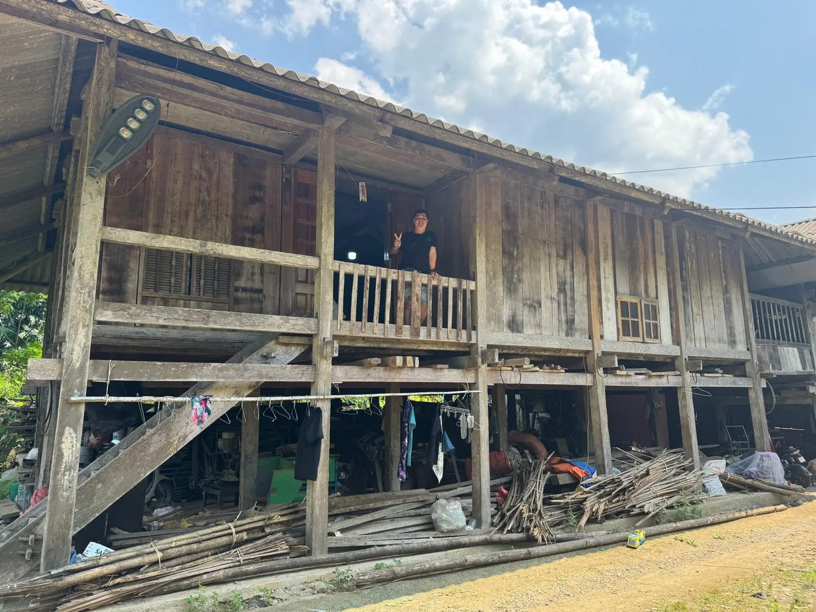 A wooden stilt house homestay on the loop, a guest waving from the balcony