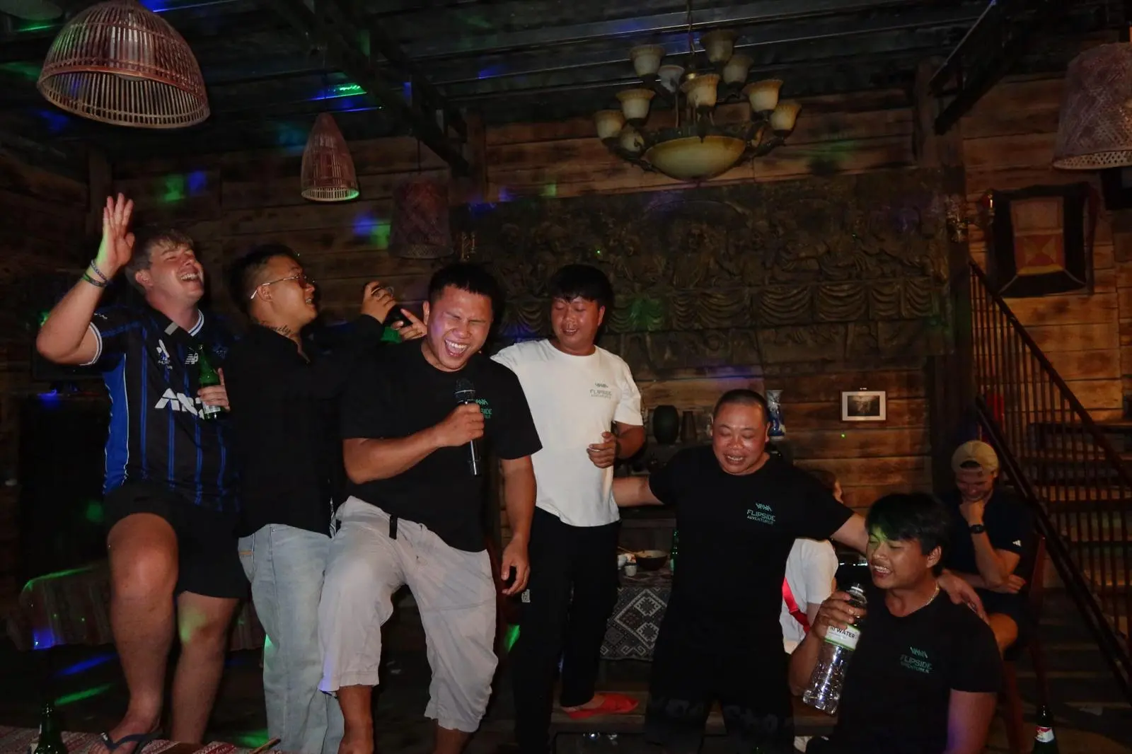 Guides and guests singing into a microphone together in the evening